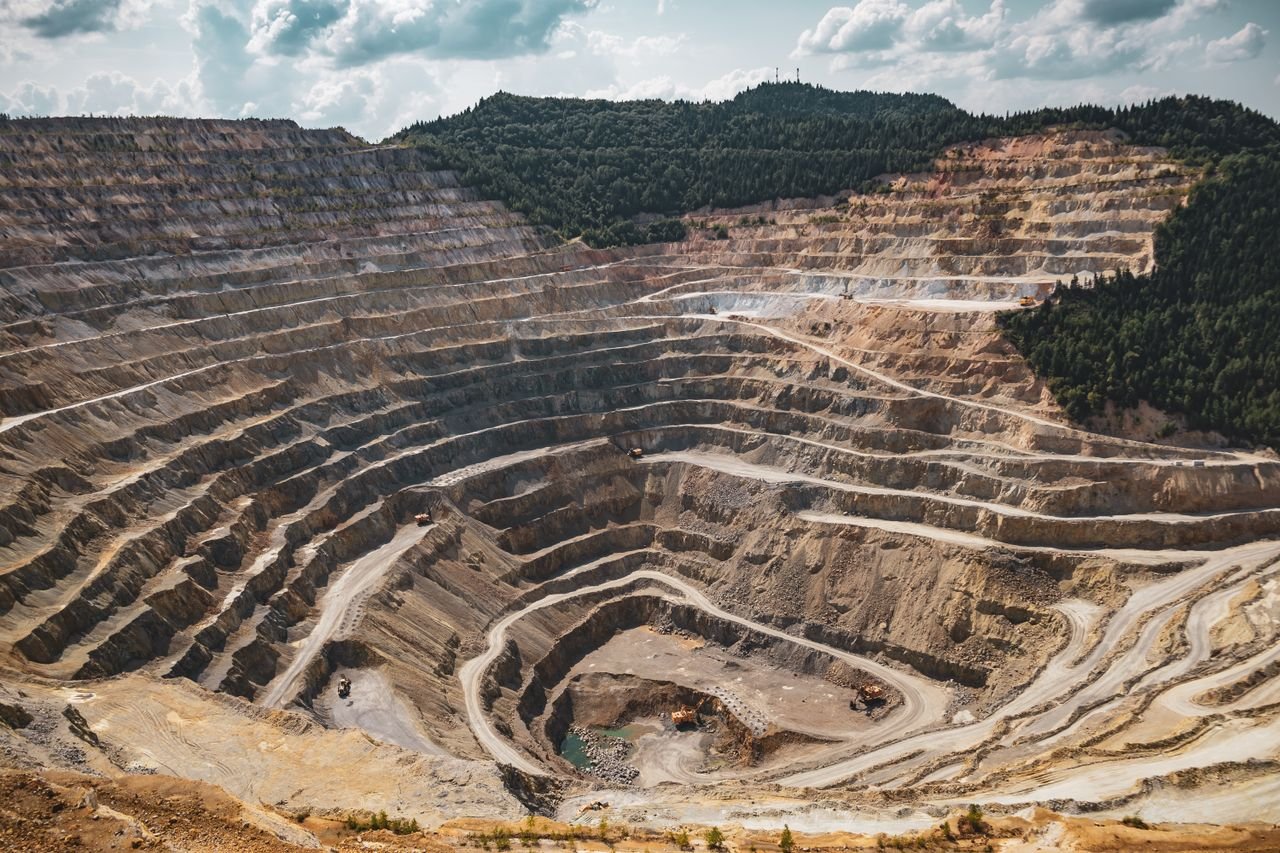 Industrias Aerial view of a large open-pit mine with terraced excavation during summer.